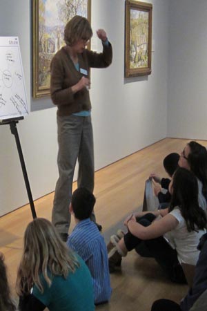 In teaching about comparison and contrast, docent Alice Gilbert shows students two different paintings that have horses as the main subject.