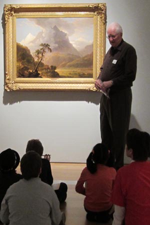 Jerry Mears, volunteer docent, talks to the third-graders about why this painting shown here is one of his favorites.