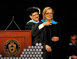 Dr. Olivarez officially named Ellen Satterlee an Honorary Doctor of Public Policy by laying the blue doctoral hood over her shoulders during graduation ceremonies in Aquinas’s field house.